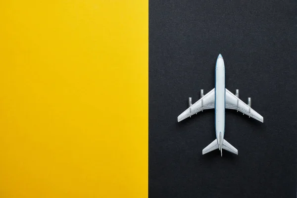 Airplane on black and yellow background with copy space and top view.