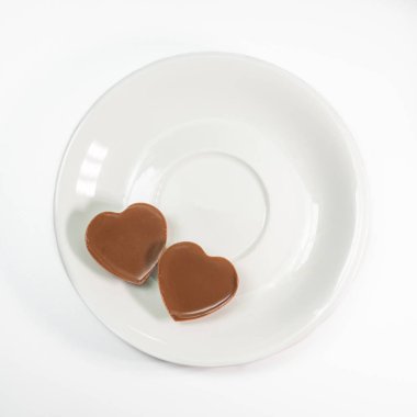 Love Heart 'ın yakın çekimi çikolatayı beyaz arka planda kahve tabağında şekillendirir..