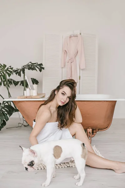 Wonderful sexy girl is seating near the bathtube with her bulldog — Stock Photo, Image