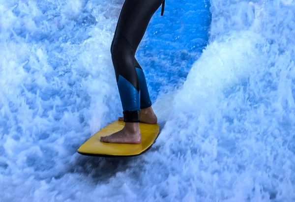 Surfer's legs closeup against a background of blue bubbling — Stock Photo, Image