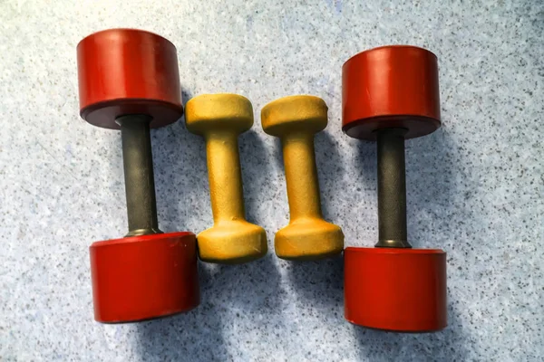 Top view of four red and yellow dumbbells — Stock Photo, Image