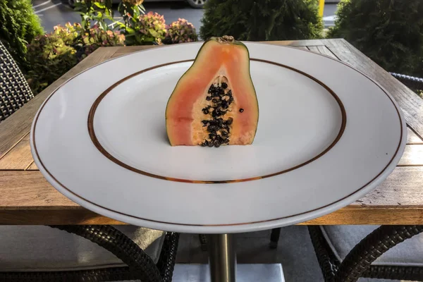 Taze sulu yarım papaya altın bir sınır ile beyaz bir plaka üzerinde