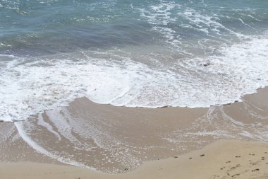 Köpüklü dalgalar kumlu bir plaj üzerinde