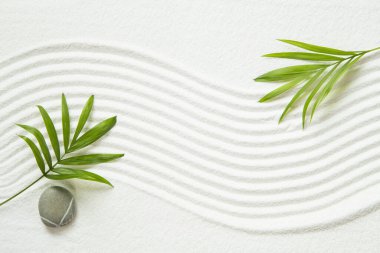 Zen deseni beyaz kumda, palmiye yapraklarıyla.