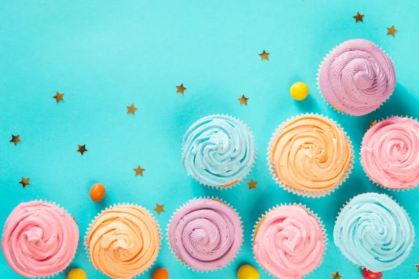 Colorful birthday cupcakes on blue background