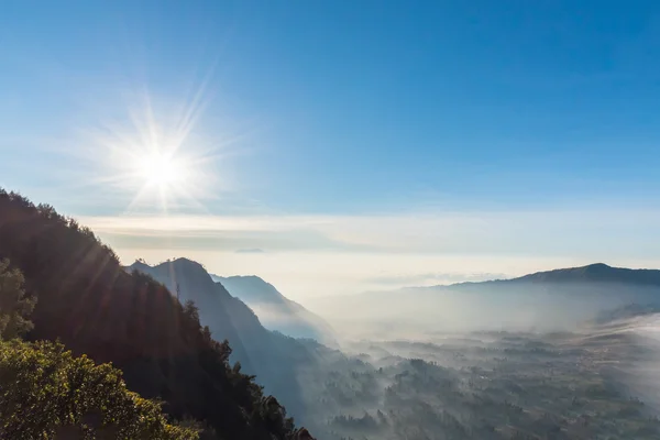 Valle de la montaña fue cubierto por la niebla de la mañana después del amanecer con el sol y el cielo azul claro . — Foto de Stock