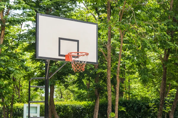 Basketball hoop with green trees on background.