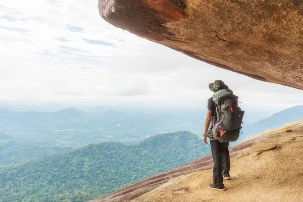 Турист с рюкзаком, стоящим на вершине горы и наслаждающийся тропическими лесами . — стоковое фото