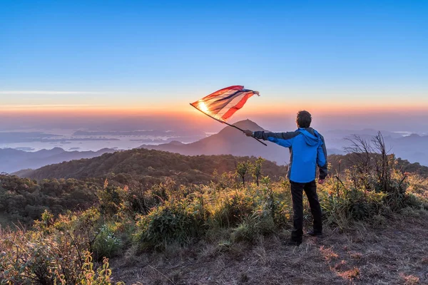 Giovane uomo in piedi sulla cima della montagna e godere della vista sul tramonto . — Foto Stock