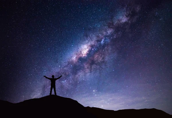 Vía Láctea paisaje. Silueta del hombre feliz de pie en la cima de la montaña con cielo nocturno y estrella brillante en el fondo . —  Fotos de Stock