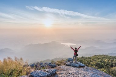 Kadın başarılı Yayilim el cliff üzerinde tırmanma ve gündoğumu manzarasının tadını çıkarın.