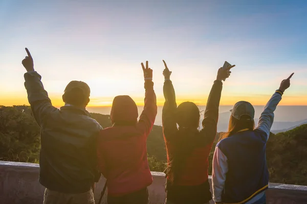 Mutlu insanlar ellerini bir güneş arka plan ile yükselterek silüeti.