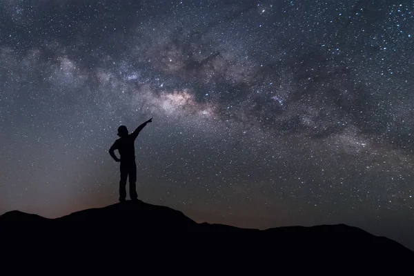 银河景观。幸福的女人站在山与夜晚的天空和明亮的星星，在背景上的剪影. — 图库照片