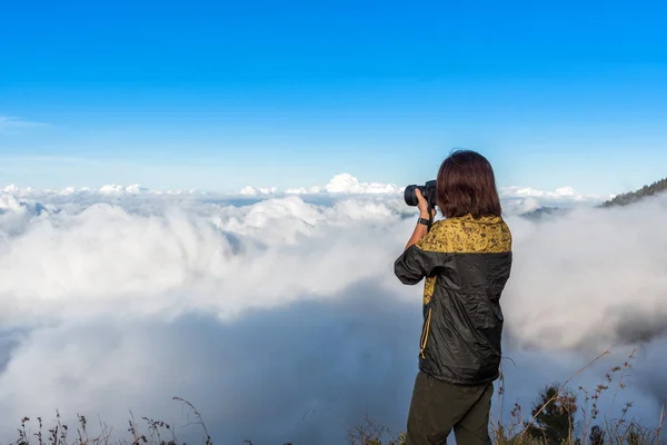 Женщина-турист носить желтый анб черный пиджак, фотографируя, наслаждаться и доволен видом на вершину горы после завершения восхождения на гору Ринджани, Ломбок, Индонезия . — стоковое фото