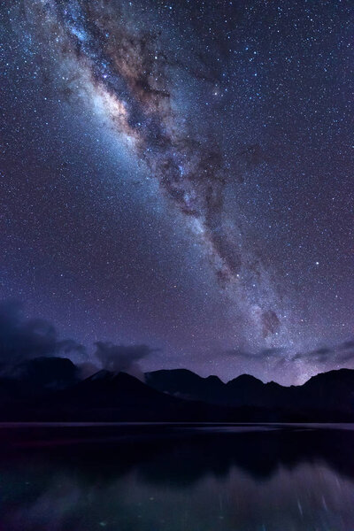Milky Way landscape. Clearly Milky way above Lake Segara Anak inside crater of Rinjani mountain on night sky. Lombok island, Indonesia.
