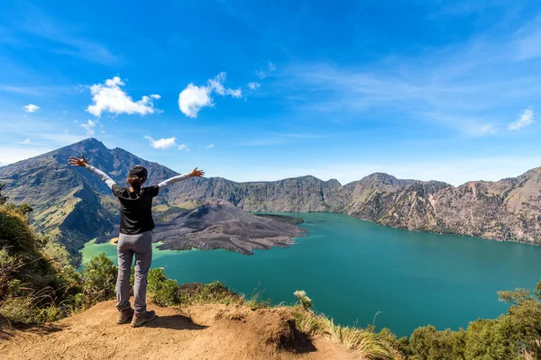 Женщина протягивает руку, наслаждается и доволен действующим вулканом Бару Яри, озером Сегара-Анак и вершиной горы Ринджани после завершения восхождения на гору Ринджани, Ломбок, Индонезия . — стоковое фото