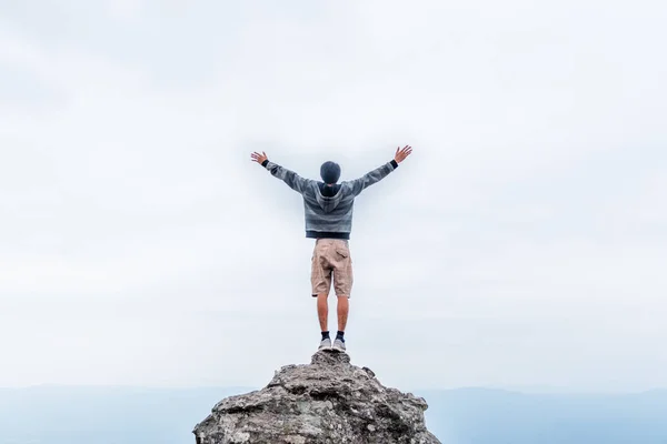 Giovane rimanere sulla roccia e stendere la mano per godersi la vista del cielo . — Foto Stock