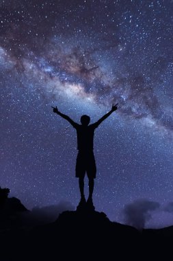 Samanyolu manzara. Mutlu adam gece gökyüzü ve arka plan üzerinde parlak yıldız ile dağın tepesinde duran silüeti.