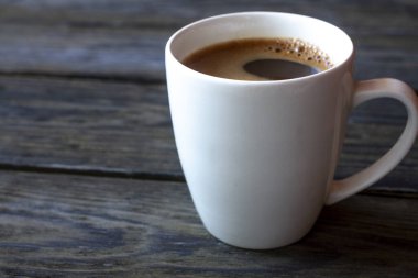 Açık arkaplanda beyaz bir fincanda bir fincan kahve.