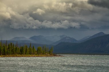 Bulutlar dağlar ve büyük göl üzerinde.