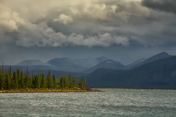Bulutlar dağlar ve büyük göl üzerinde.
