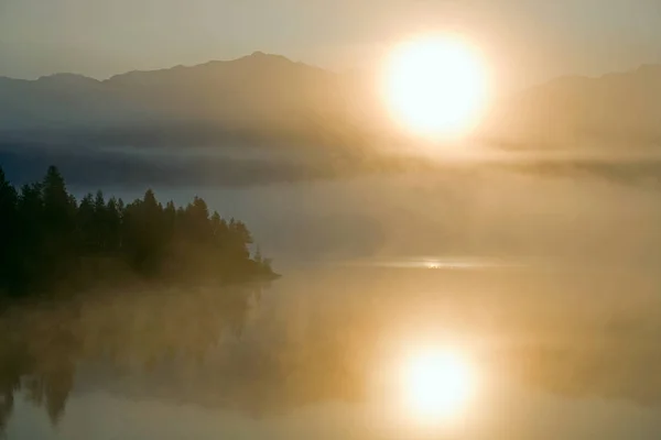 Fog on the mountain lake and the rising sun. — Stock Photo, Image