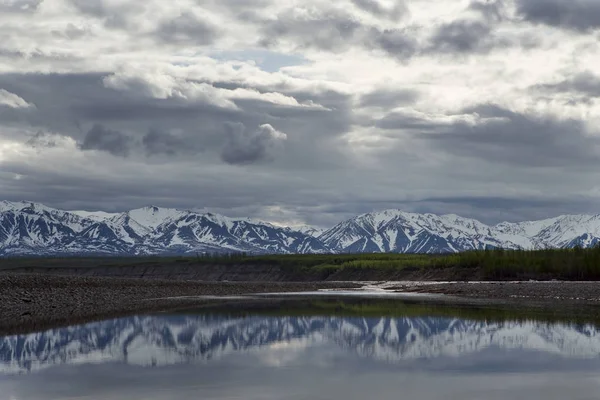 Montagne primaverili con resti di neve e il riflesso nel fiume . — Foto Stock