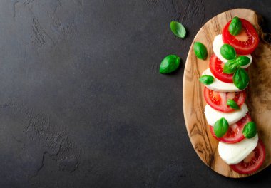 Domates ve mozzarella peyniri dilimlenmiş zeytin t yapılmış ahşap bir gemide