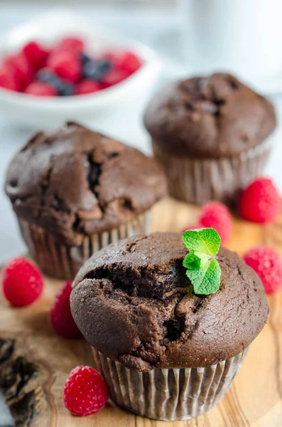 Tres magdalenas de chocolate en una tabla de madera con frambuesas frescas — Foto de Stock