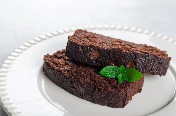 İki çikolatalı kek nane yaprakları üzerinde beyaz bir hizmet ile dilim 