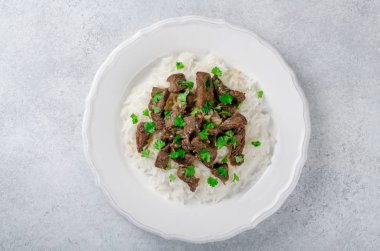 Maydanoz bir li üzerinde beyaz bir tabakta ile kızarmış biftek ve pirinç pişmiş