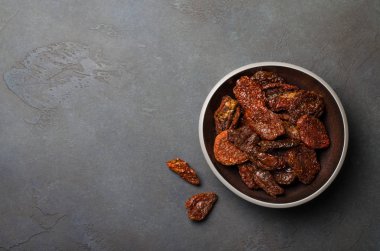 Kurutulmuş domates karanlık bir taş üzerinde karanlık bir kapta backgrou kayrak