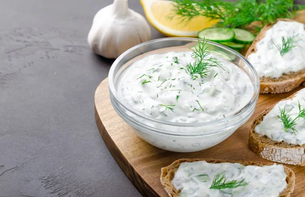 Salsa tzatziki griego casero en un tazón de vidrio con ingredientes a — Foto de Stock