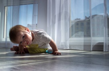 Ahşap katta oturan ve bir beyaz duvar arka plan üzerinde seyir bebek çocuk bebek yürümeye başlayan çocuk