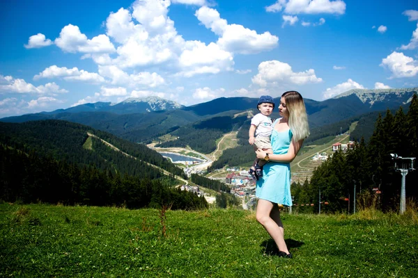 Молодая мать играет со своим маленьким сыном в горах на закате. Мама и ребенок стоят и смотрят на закат в горах . — стоковое фото