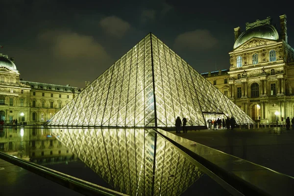 PARÍS - 11 DE MAYO: Los turistas caminan frente al Louvre, 11 de mayo de 2016 en París, Francia. El Louvre es el museo de arte más visitado del mundo y un monumento histórico . —  Fotos de Stock