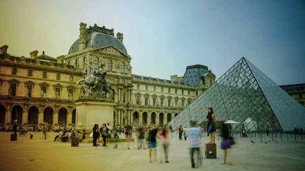 PARÍS - 11 DE MAYO: Los turistas caminan frente al Louvre, 11 de mayo de 2016 en París, Francia. El Louvre es el museo de arte más visitado del mundo y un monumento histórico . —  Fotos de Stock