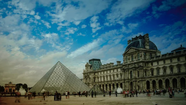 PARÍS - 11 DE MAYO: Los turistas caminan frente al Louvre, 11 de mayo de 2016 en París, Francia. El Louvre es el museo de arte más visitado del mundo y un monumento histórico . —  Fotos de Stock