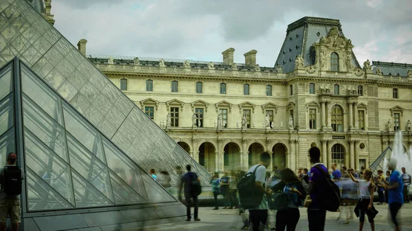 Parijs - 11 mei: Toeristen lopen voor het Louvre, Parijs, Frankrijk, 11 mei 2016. Het Louvre is de meest bezochte kunstmuseum in de wereld en een historisch monument. — Stockfoto