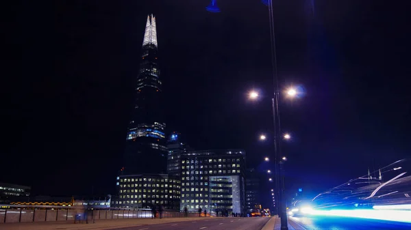 LONDRES, Reino Unido - 5 DE ABRIL: Los coches de tráfico y peatones en el Puente de Londres en la noche con The Shard en segundo plano en abril en Londres, Reino Unido. larga exposición, semáforo — Foto de Stock