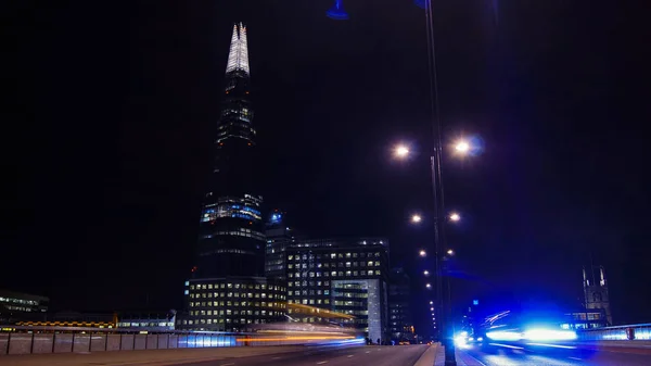 LONDRES, Reino Unido - 5 DE ABRIL: Carros de trânsito e pedestres na London Bridge durante a noite com o The Shard em segundo plano em abril em Londres, Reino Unido. exposição longa, semáforo — Fotografia de Stock