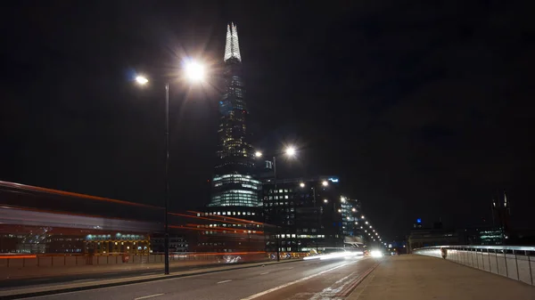 London, Egyesült Királyság - április 5-én: Forgalom autók és gyalogosok-a London Bridge-az éjszaka a Szilánk a háttérben április-ben London, Egyesült Királyság. hosszú expozíció, közlekedési lámpa — Stock Fotó