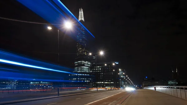 LONDRES, Reino Unido - 5 DE ABRIL: Carros de trânsito e pedestres na London Bridge durante a noite com o The Shard em segundo plano em abril em Londres, Reino Unido. exposição longa, semáforo — Fotografia de Stock