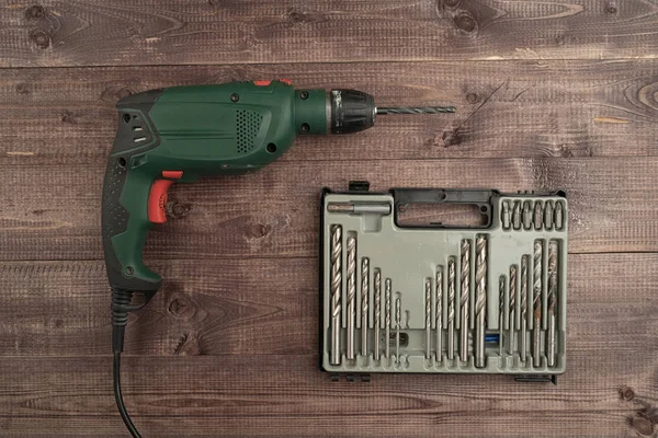 An Electrical drill and twist bits on a wooden table