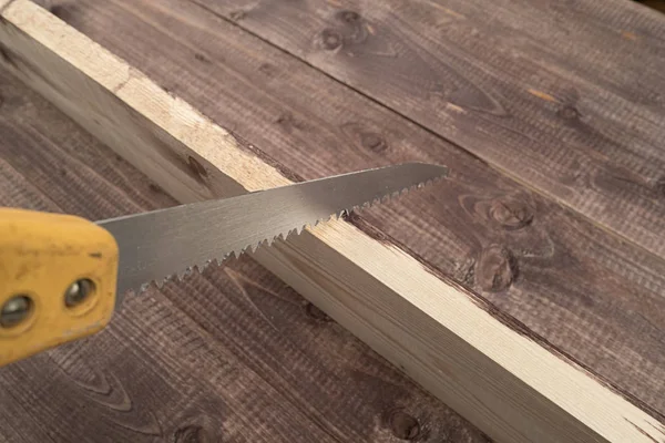 A metal hand saw on a wooden table