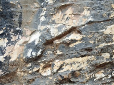 Tepenin yamacında. Kesiğin üzerinde farklı kaya türleri var.