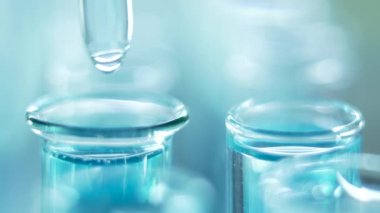 Bir laboratuarda, pipetli bir bilim adamı test tüplerindeki DNA ve molekülleri ayırmak için mavi bir sıvıyı analiz eder. Sıvıyla çalışan doktor..