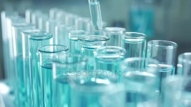 Bir laboratuarda, pipetli bir bilim adamı test tüplerindeki DNA ve molekülleri ayırmak için mavi bir sıvıyı analiz eder. Sıvıyla çalışan doktor..