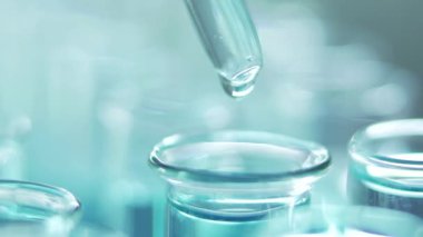 Bir laboratuarda, pipetli bir bilim adamı test tüplerindeki DNA ve molekülleri ayırmak için mavi bir sıvıyı analiz eder. Sıvıyla çalışan doktor..