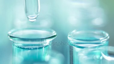 Bir laboratuarda, pipetli bir bilim adamı test tüplerindeki DNA ve molekülleri ayırmak için mavi bir sıvıyı analiz eder. Sıvıyla çalışan doktor..